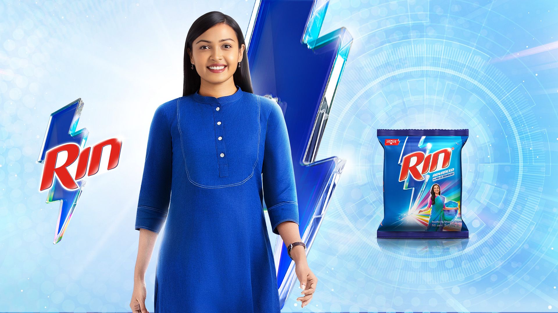 A woman in a blue dress with a packet of Rin Advanced