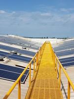 A yellow metal walkway runs through the centre of an array of solar panels on the roof of a Unilever building in India.