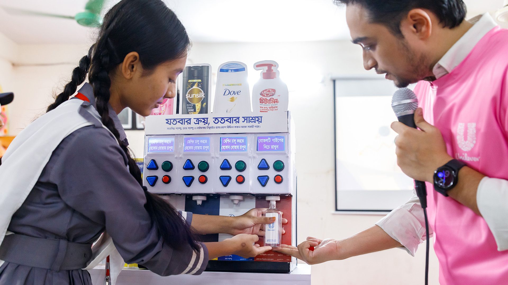 Volunteer guiding a student to use the URefill machine for refilling a bottle