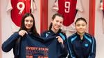 Three girls, sitting in the Arsenal FC changing room, holding a t-shirt that reads “Every stain should be part of the game”.
